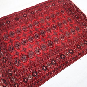 May include: A red rug with a traditional Persian design. The rug has a central medallion and a border with intricate patterns.