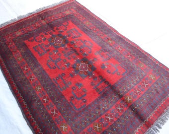 Puede incluir: Una alfombra roja y azul con un borde de flecos. La alfombra tiene un diseño tradicional con detalles intrincados.