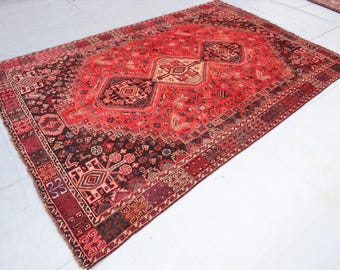 May include: A red, black, and cream vintage rug with a geometric pattern. The rug has a fringed edge and is made of wool.