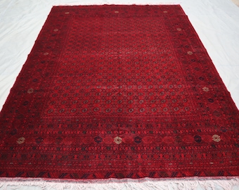 May include: A red rug with a detailed geometric pattern and a white fringe border. The rug has a traditional Persian design.