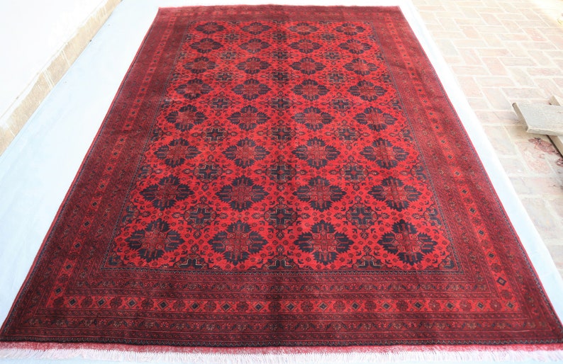 May include: A red and black rug with a traditional Persian design. The rug has a detailed border and a central medallion.