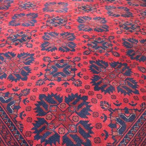 May include: A red rug with a blue and white geometric pattern. The rug has a traditional design with intricate details.