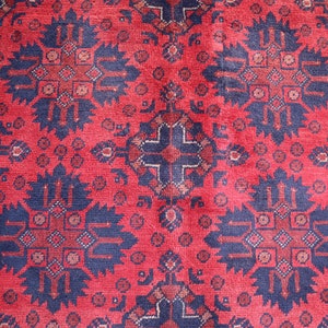 May include: A red rug with a repeating pattern of blue and white geometric shapes. The rug has a traditional design.