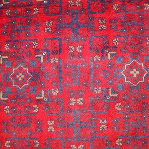 May include: A red rug with a blue and white geometric pattern. The rug has a traditional design with repeating motifs.