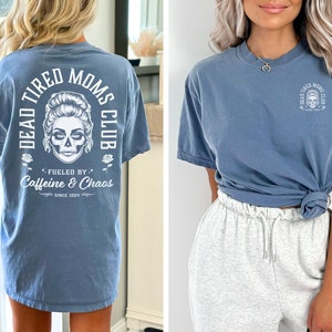 Peut inclure: T-shirt bleu jean avec l'inscription "DEAD TIRED MOMS CLUB" et un motif de cr&acirc;ne. Le dos du t-shirt porte &eacute;galement l'inscription "FUELED BY Caffeine & Chaos SINCE 2024". Le t-shirt a une coupe d&eacute;contract&eacute;e.