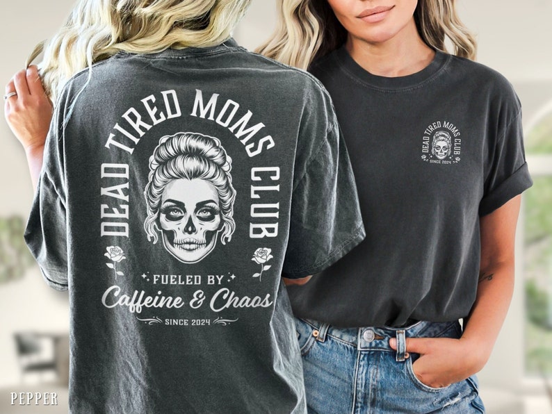 Peut inclure: T-shirt gris fonc&eacute; avec un motif de cr&acirc;ne et le texte "DEAD TIRED MOMS CLUB". Le dos du t-shirt affiche les mots "Fueled by Caffeine & Chaos" et "Since 2024". Le devant pr&eacute;sente une version plus petite du motif.