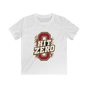 May include: A white short-sleeved t-shirt featuring a central graphic of a large maroon letter O with a black and gold outline. Overlaid on the letter is the text HIT ZERO in bold white letters with black outlines, surrounded by gold starbursts.