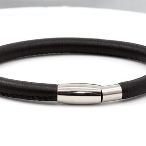 May include: A black leather bracelet with a silver magnetic clasp.