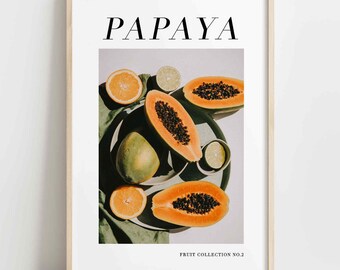 May include: A framed print with the word "PAPAYA" in black text at the top. The print features a still life of papaya fruit, limes, and oranges on a green cloth and a white plate. The text "FRUIT COLLECTION NO. 2" is at the bottom of the print.