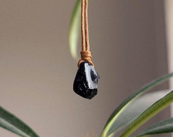 Puede incluir: Un colgante de obsidiana negra en un collar de cordón marrón.