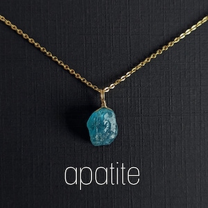 May include: A gold chain necklace with a blue apatite pendant. The pendant is a rough, natural stone.