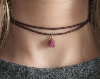 Może przedstawiać: Brązowy skórzany naszyjnik choker z wisiorem z różowego kamienia szlachetnego.