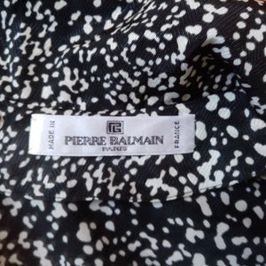 Puede incluir: Tejido estampado en blanco y negro con un dise&ntilde;o de lunares repetido. La etiqueta dice "PIERRE BALMAIN PARIS FRANCE" y "MADE IN FRANCE". El tejido tiene un aspecto sedoso.