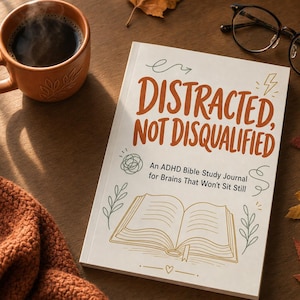 May include: A white book titled Distracted, Not Disqualified: An ADHD Bible Study Journal for Brains That Won't Sit Still, featuring orange text and line art of an open book, surrounded by a coffee mug, glasses, and autumn leaves.