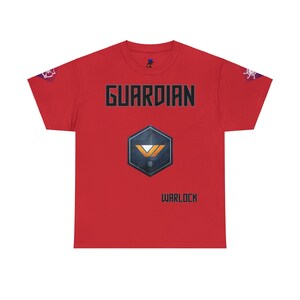 May include: Red t-shirt with the word "GUARDIAN" in black and gray block letters. Below the word is a geometric emblem with a blue, orange, and white design. The word "WARLOCK" is printed below the emblem. Small decorative elements are on the sleeves.