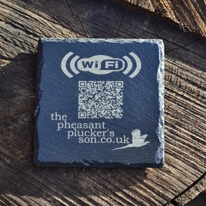 Op de afbeelding: Een zwart leisteen bord met een wit Wi-Fi symbool, een QR-code en de tekst "the pheasant plucker's son.co.uk".