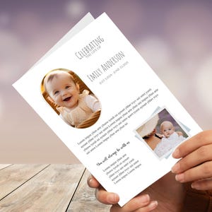 Puede incluir: Una tarjeta conmemorativa blanca con el texto "Celebrando la vida de Emily Anderson" y fechas. La tarjeta presenta dos fotos de un bebé e incluye texto decorativo. Sostenida en las manos de una persona.