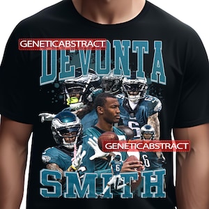 Puede incluir: Camiseta negra con un collage de jugadores de fútbol americano con uniformes de los Eagles. La camiseta muestra el nombre "DEVONTA SMITH" en letras turquesas. El texto "GENETICABSTRACT" también es visible.