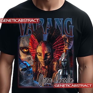 May include: Black t-shirt featuring a graphic design with the word "VARANG" in blue and white, and the name "Oona Chaplin". The design includes multiple faces with tribal-like makeup and headdresses. The text "GENETICABSTRACT" is also present.