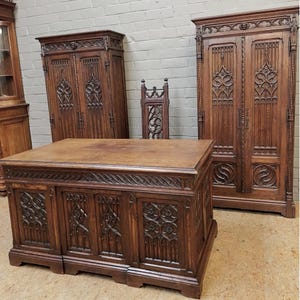 May include: A collection of antique wooden furniture, including a large desk, two tall cabinets, and a chair. The furniture features intricate carved details and a rich, dark brown finish. The desk has three doors and a detailed top.