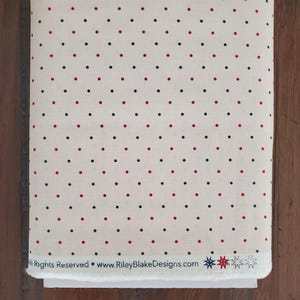May include: A roll of fabric featuring a cream-coloured background adorned with a repeating pattern of red and navy blue polka dots. The fabric has the text "All Rights Reserved &bull; www.RileyBlakeDesigns.com".