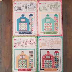 Peut inclure: Quatre patrons de quilt colorés, intitulés "Quilt Seeds", avec des motifs de grange pour chaque saison. Chaque livre présente une palette de couleurs de grange différente : bleu, vert, beige et rouge. Le texte "Spring Barn", "Summer Barn", "Autumn Barn" et "Winter Barn" est affiché.