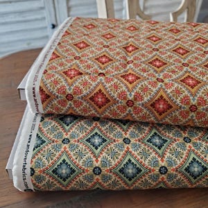May include: Two rolls of patterned fabric. The top roll has a design in red, gold, and cream. The bottom roll features a similar pattern in blue, green, and cream. The fabric is likely cotton or a similar material, suitable for various sewing projects.