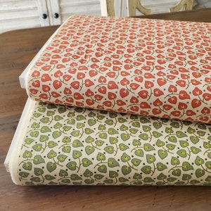 May include: Two rolls of fabric with floral patterns. One roll features a repeating pattern of red heart-shaped flowers with green stems and gray dots on a cream background. The other roll has green leaves with yellow accents.