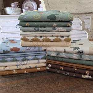 May include: A collection of patterned fabrics in a variety of designs, such as trees, mushrooms, and geometric shapes. The colour scheme features greens, blues, browns, and cream. The fabrics are likely cotton or a similar material, ideal for quilting or craft projects.