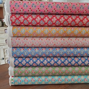 Puede incluir: Una pila de rollos de tela en varios colores, incluyendo rosa, rojo, amarillo y azul. Cada rollo presenta un patrón floral repetido con pequeñas flores en colores contrastantes. La tela parece ser de algodón o un material similar, adecuado para costura.