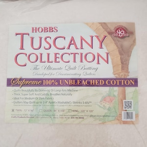 May include: A white Hobbs Tuscany Collection quilt batting package. The package features the text "Tuscany Collection" in a pink font, and "Supreme 100% Unbleached Cotton". It includes size options: Twin 72" x 96", Queen 96" x 108", and King 120" x 120".