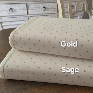 May include: Two fabric bolts, one on top of the other, with a cream base and gold polka dots. The bottom bolt is labelled "Sage" and the top bolt is labelled "Gold". The fabric is from the "Basket Quilts for Andover Fabric" collection.