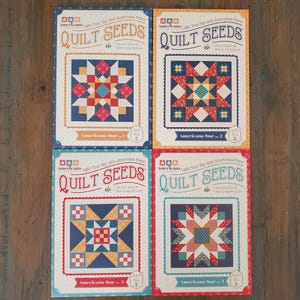May include: Four quilt pattern books are displayed, each featuring a different star design. The covers have a vintage aesthetic with the text "QUILT SEEDS" and "Americana Star" in a decorative font. The color palette includes red, blue, yellow, and white.