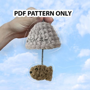 May include: A PDF pattern for a crocheted cloud-shaped toy with a fish hanging from it. The cloud is gray and has Korean writing on it. The fish is brown and has black eyes.