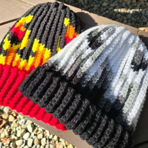 May include: Two crocheted hats, one with a black and red base and a yellow, orange, and red pattern, and the other with a black and white striped pattern.