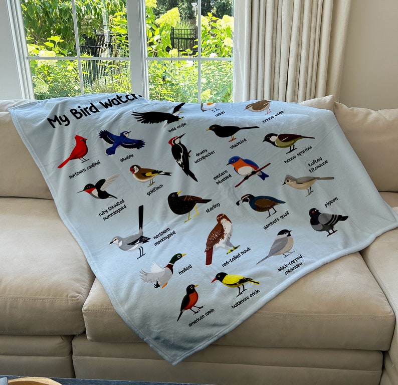 May include: A blue fleece blanket with a white background and colorful illustrations of different birds. The text "My Bird Watch" is at the top of the blanket.