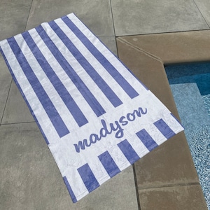 May include: A white and blue striped beach towel with the name "mady son" written in purple cursive.