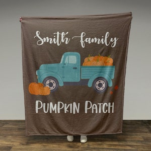 May include: A brown fleece blanket with the text "Smith family Pumpkin Patch" and a blue pickup truck carrying pumpkins.