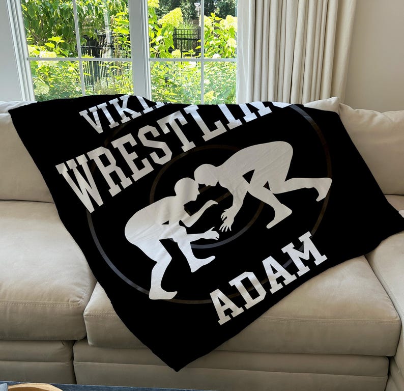 May include: Black fleece blanket with white text that reads "Viking Wrestling Adam" and a graphic of two wrestlers in silhouette.