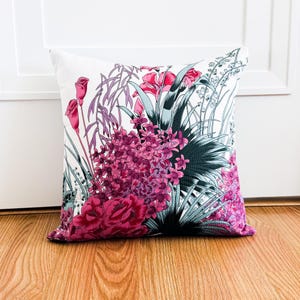 May include: A white cushion with a floral print featuring pink and green flowers. The cushion is on a wooden floor.