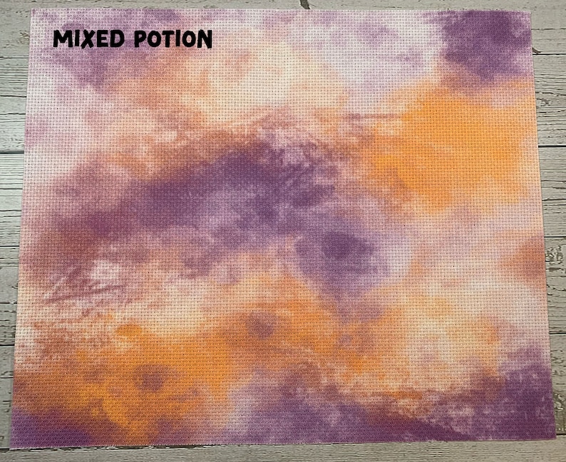 May include: A cross-stitch fabric with a blended design of orange, purple, and cream colors. The words "MIXED POTION" are printed in black at the top. The fabric has a grid-like texture.