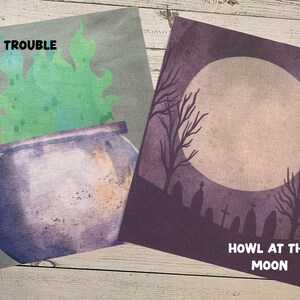 May include: Two Halloween-themed prints. One features a purple cauldron with green smoke and the text "TOIL & TROUBLE." The other depicts a full moon, bare trees, and tombstones with the text "HOWL AT THE MOON."