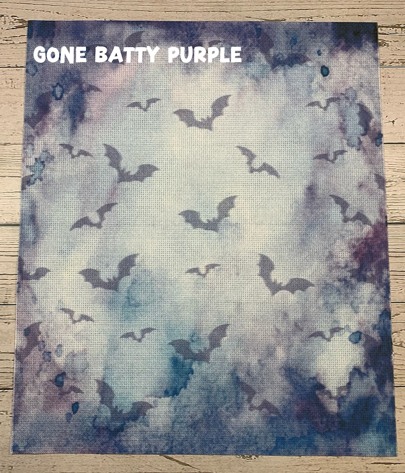 May include: A square fabric with a watercolor-style background in shades of blue and purple. Silhouetted bats are scattered across the surface. The text "GONE BATTY PURPLE" is at the top.