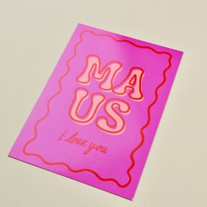 Könnte beinhalten: Eine rosa Grußkarte mit den Worten "MA US" in einer Retro-Schriftart, rot umrandet. Darunter steht der Satz "I love you" in kursiver Schrift. Die Karte hat einen wellenförmigen roten Rand.