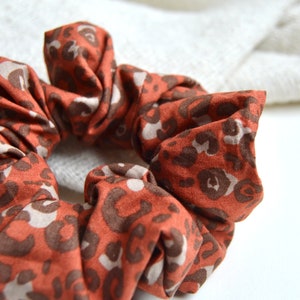 Könnte beinhalten: Ein braunes und beiges Haargummi mit Leopardenmuster.