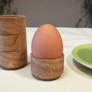 Könnte beinhalten: Ein braunes Ei sitzt in einem Eierbecher aus Holz. Der Eierbecher besteht aus übereinander gestapelten Holzringen. Ein zweiter Satz übereinander gestapelter Holzringe befindet sich links vom Eierbecher.
