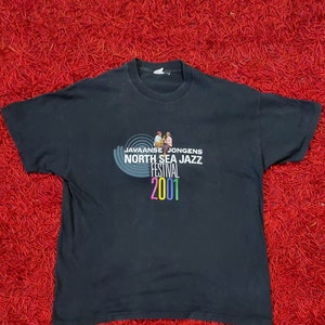 May include: Black t-shirt with a graphic of a band playing music. The text reads "Javaanse Jongens North Sea Jazz Festival 2001".