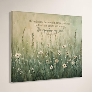 May include: Canvas art print featuring a serene meadow scene with white flowers and tall green grass. The artwork includes the text "He makes me lie down in green pastures... He refreshes my soul." Psalm 23:2-3.