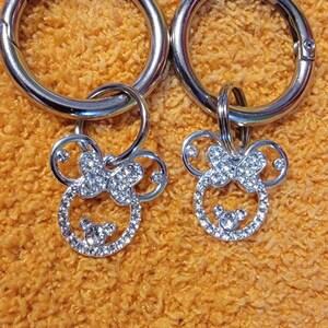May include: Two silver keychains with a silver ring and a rhinestone-encrusted Mickey Mouse head charm.