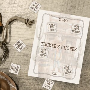 May include: A western-themed chore chart with the text "Tucker's Chores" and chore prompts. A brown cowboy boot, rope, and hat are scattered around the chart. Chore prompts include "Put Toys Away" and "Brush My Teeth."
